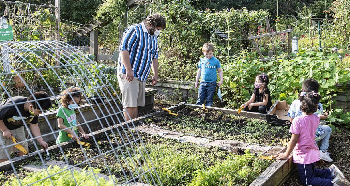 An adult and several children are working in the School of Education's urban garden.