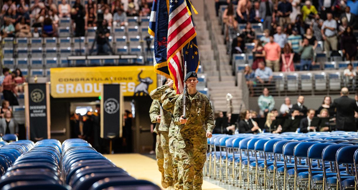 Military students carry in flags at commencement.