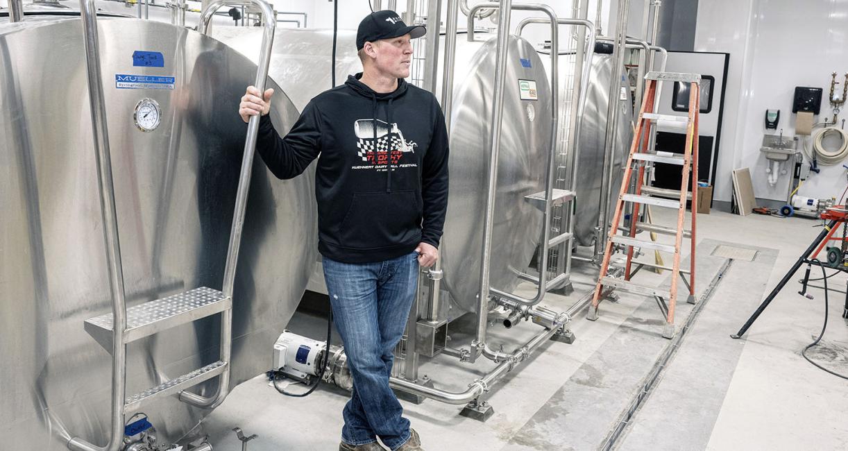 Andrew Kuehnert is leaning against a milk tank.