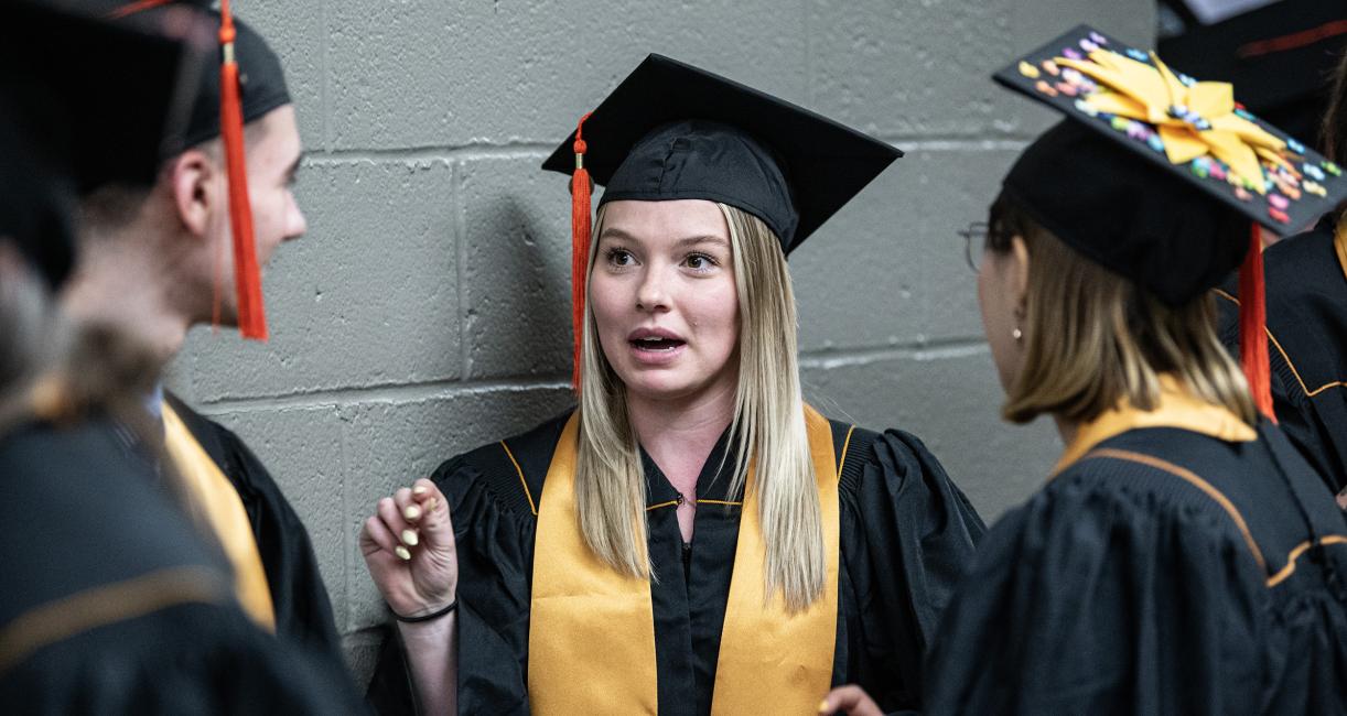 Graduating students chat in the hallway before commencement begins.