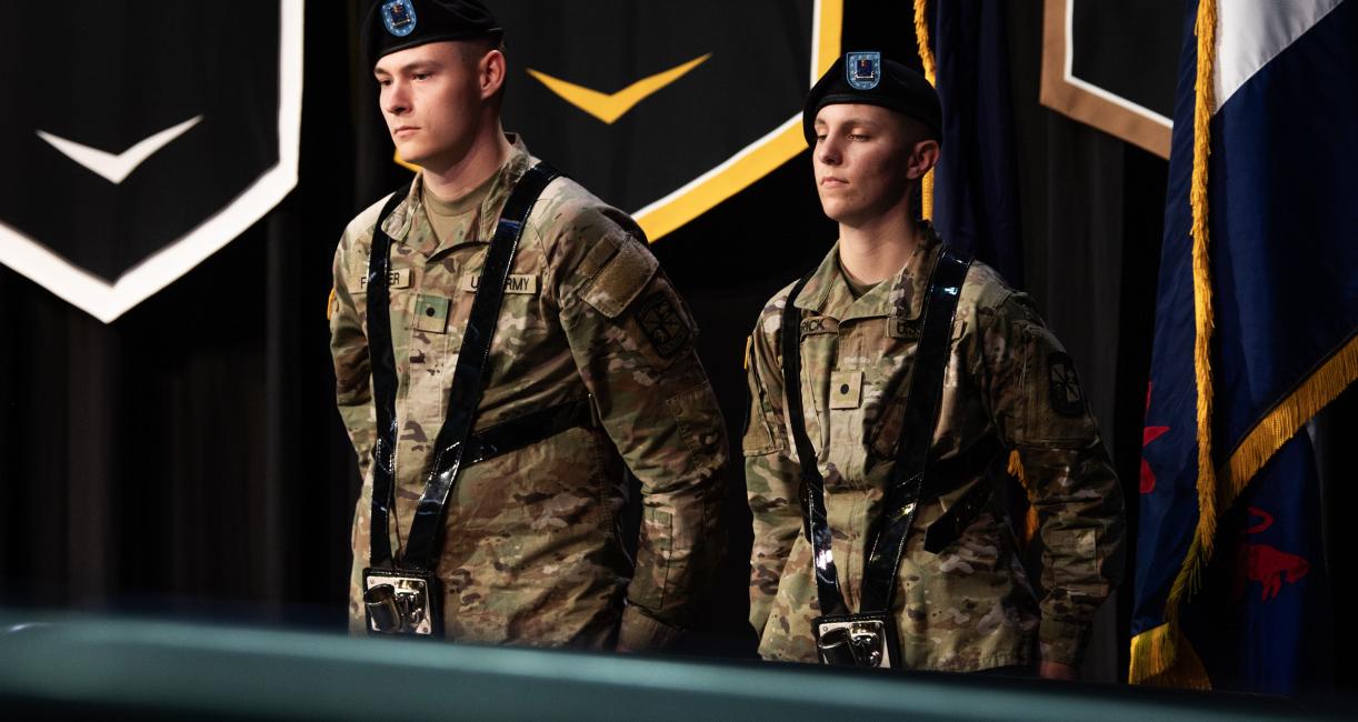 ROTC students stand near the flags on stage.