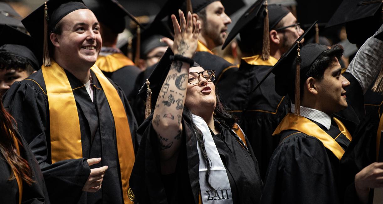 Graduating students wave to friends and guests in the crowd.