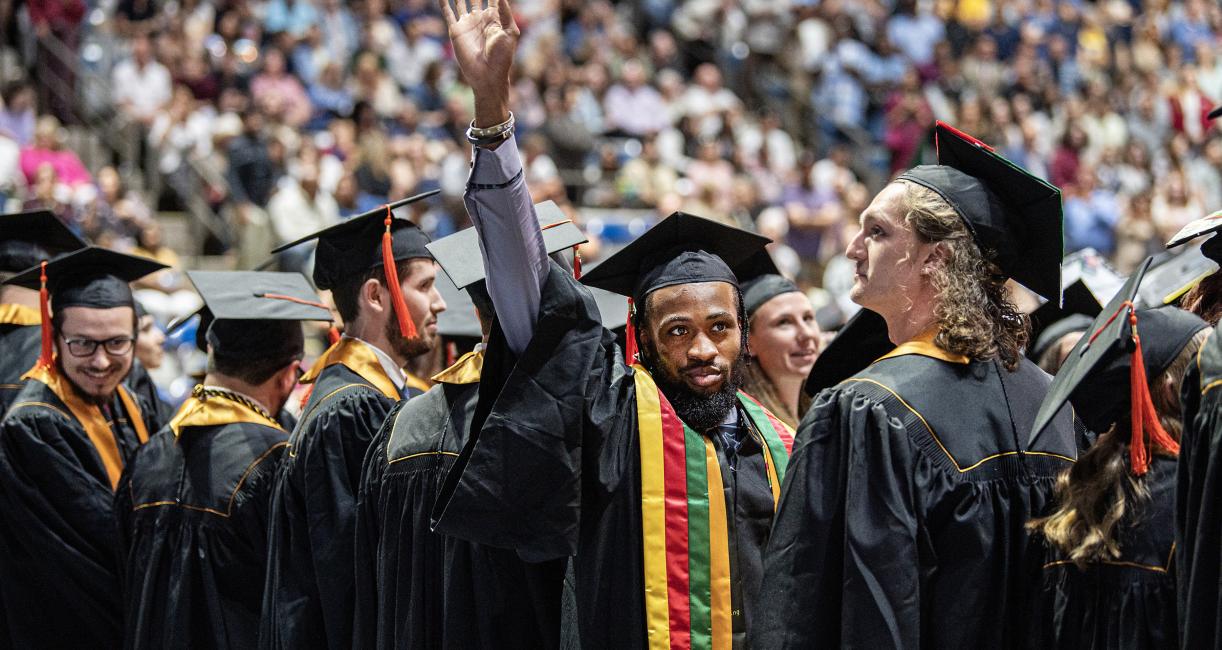 Students in caps and gowns in the arena at the Coliseum.