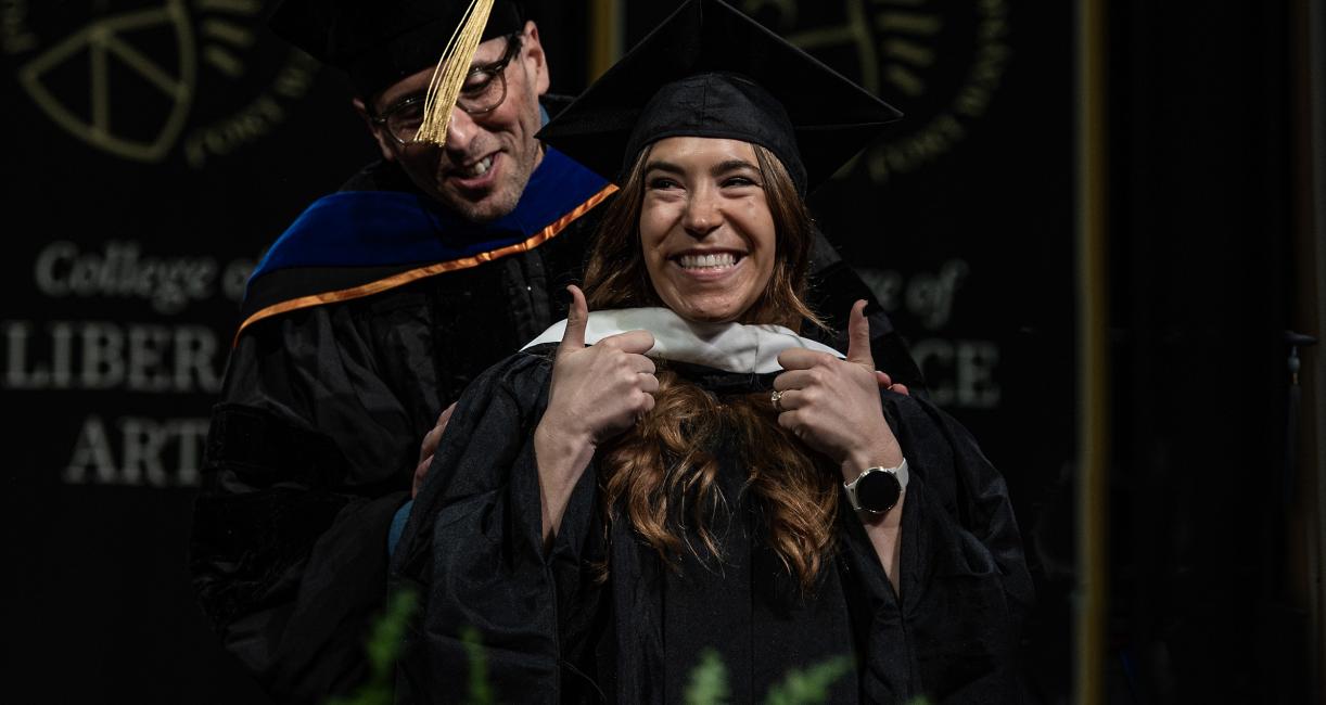 Graduate student gives a double thumbs-up to the crowd.