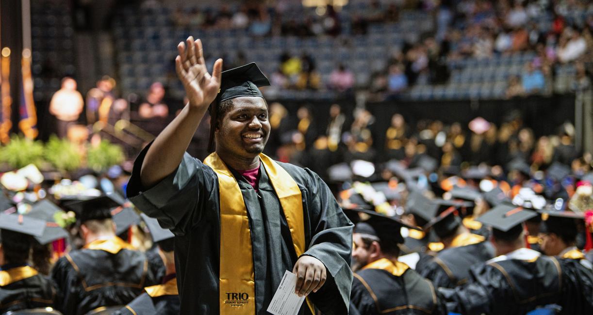 Graduating student waves to commencement guests.