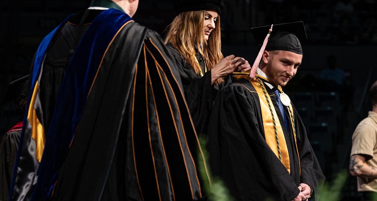 Graduating student on stage with faculty.