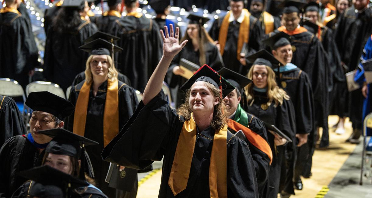 Graduating student waves to crowd.