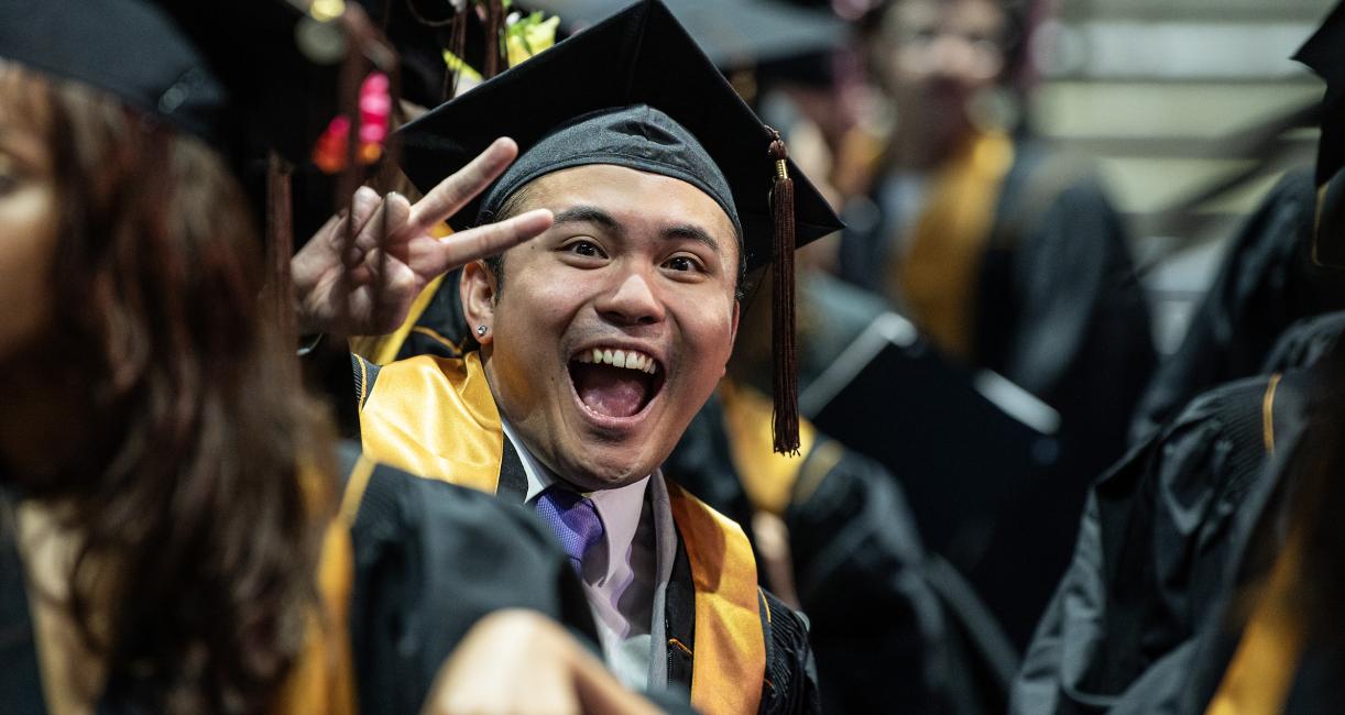 Graduating student holds up peace sign.