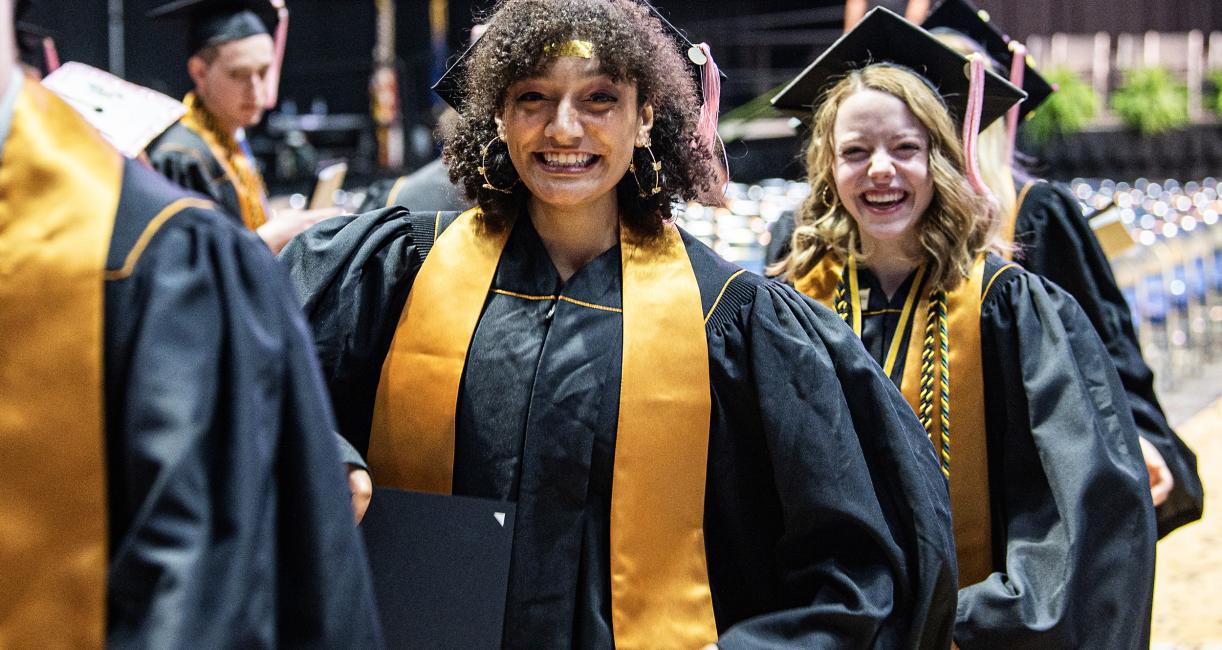 Students in caps and gowns leave the arena.