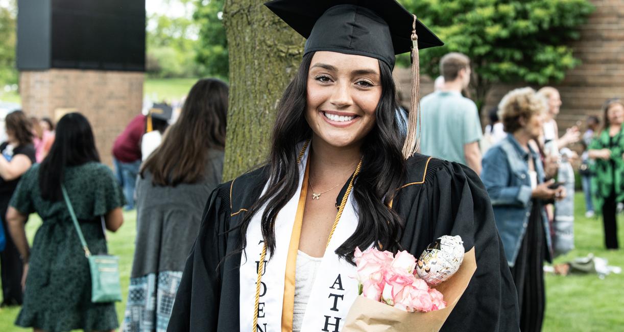 Graduate holding flowers.