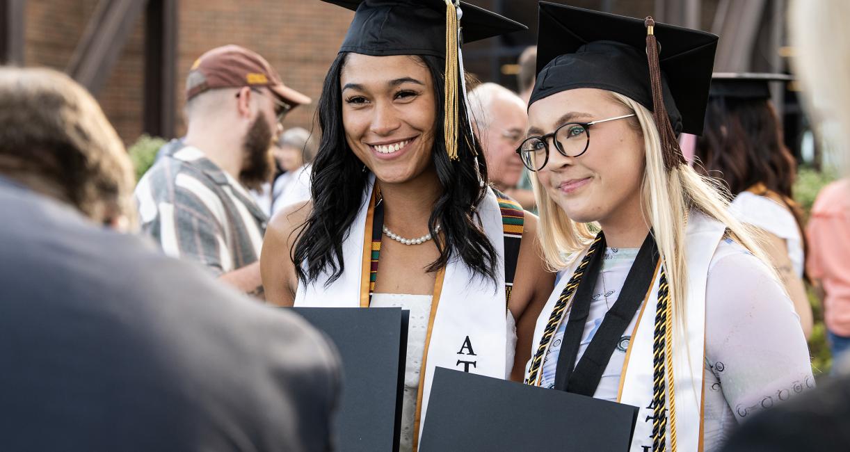 Students pose for photos with degree holder