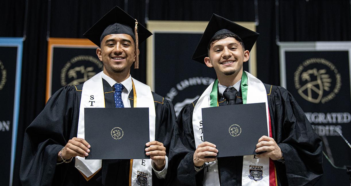 Two students display their diplomas