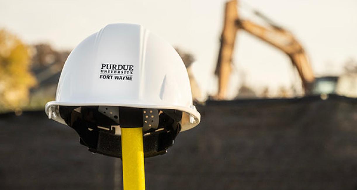 Construction helmet on a shovel with a backhoe in the background